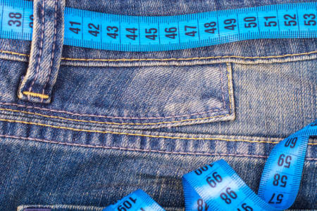 Concept of healthy lifestyle, weight loss. Jeans with measuring tapeの写真素材