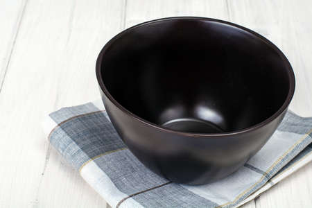 Brown ceramic bowl on white wooden backgroundの写真素材