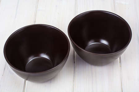 Brown ceramic bowl on white wooden backgroundの写真素材