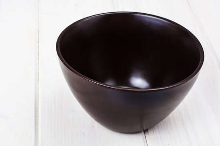 Brown ceramic bowl on white wooden backgroundの写真素材