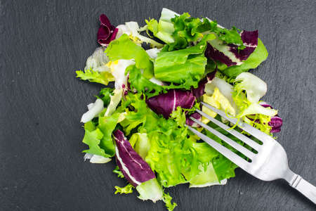 Concept of healthy meal. Fresh leaves of different salads on blackの写真素材