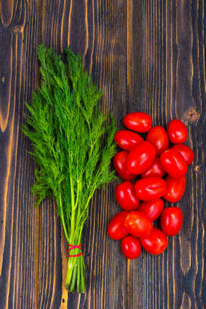Red tomatoes and green dill on wooden backgroundの写真素材