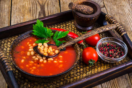 Red Ukrainian borsch with white beans on wooden tray. Close-up. The concept of nutritionの写真素材