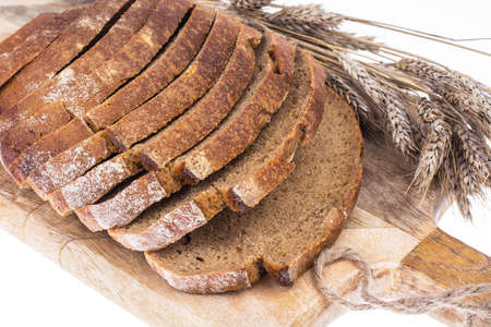 Rye bread, sliced on a kitchen wooden board, ears with grains. Studio Photo