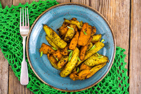 Baked vegetables, potatoes and pumpkin with herbs and spicesの写真素材