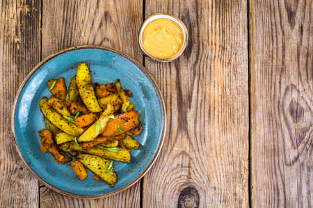 Baked vegetables, potatoes and pumpkin with herbs and spicesの写真素材