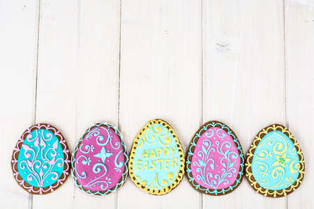 Easter homemade baked gingerbread cookies in the form of eggs with different pattern of icing on plateの写真素材