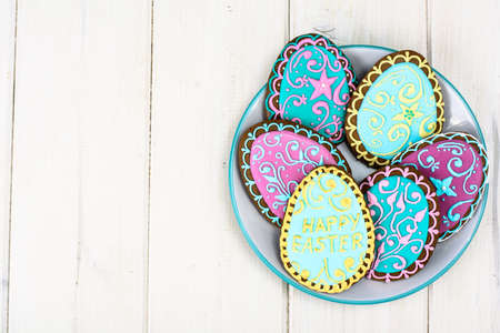 Easter homemade baked gingerbread cookies in the form of eggs with different pattern of icing on plateの写真素材