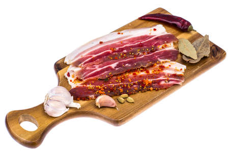 Slices of smoked bacon with light on wooden kitchen cutting boardの写真素材