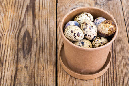 Quail eggs in cardboard box on wooden tableの写真素材
