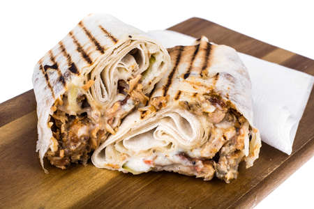 Hot shawarma roll with cheese, meat and sauce. Studio Photo