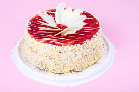 Homemade cake with red icing and white chocolate on bright colored background. Studio Photo