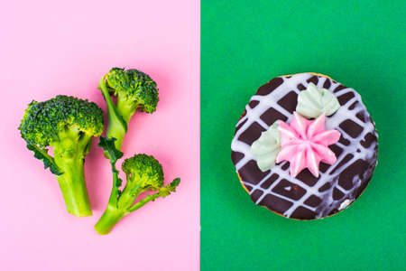 Choosing between broccoli and unhealthy food, cake bush. Concept of vegetarianism and healthy lifestyle. Studio Photoの写真素材