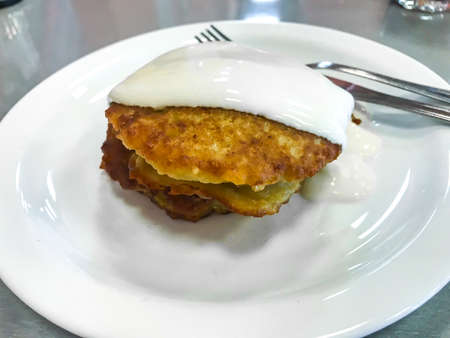 Potato pancakes with sour cream on white plateの写真素材