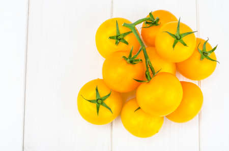 Bunch of ripe yellow tomatoes on white wooden tableの写真素材