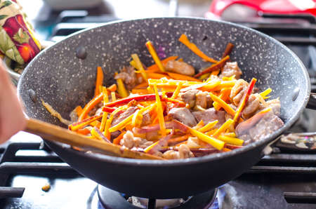 Meat with vegetables in frying pan wok on a stove.の写真素材