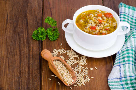 White bowl of chicken and wild rice soup with vegetables.の写真素材
