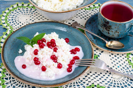 A cup of hot tea and homemade fresh cottage cheese with yogurt and red berries