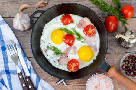 Frying pan with fried eggs, bacon and tomatoes. Studio Photo