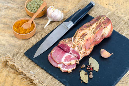 Traditional smoked pork neck with herbs and spices on black stoneの写真素材
