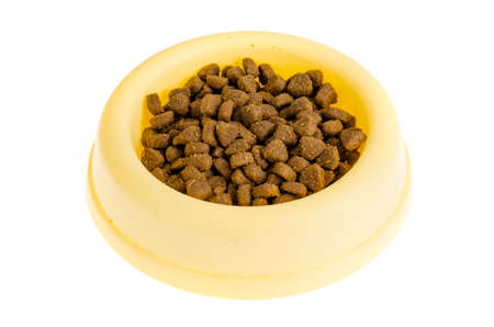 Yellow plastic bowl with dry pet food. Studio Photo