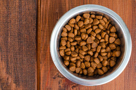 Metal bowls with various pet food. Studio Photo