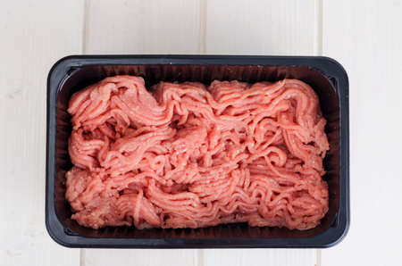 Minced meat in black plastic container. Studio Photo