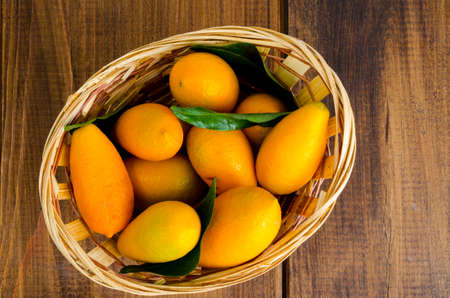 Ripe sweet orange kumquats fortunella in wooden basket. Studio Photoの写真素材
