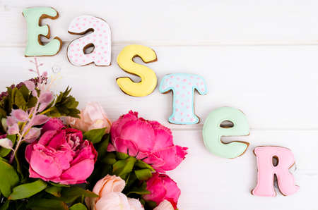 Creative greeting Happy Easter. Lettering from biscuits on white wooden background. Pastel holiday...