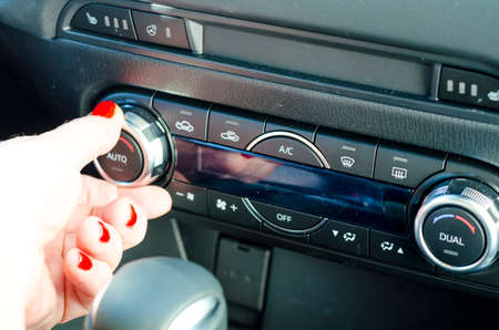 Female hand regulates climate control in car. Studio Photo