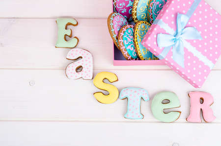 Colorful easter egg in gift box, cookies biscuits letter Easter on wood background. Studio Photoの写真素材