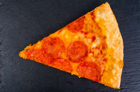 Pieces of pizza on black stone background. Studio Photo