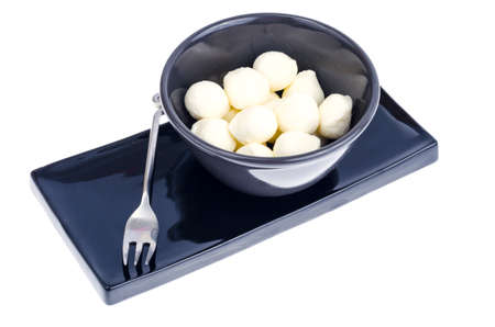 Small white mozzarella balls in black bowl. Studio Photo
