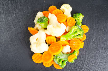 Mix of frozen vegetables on black stone background. Studio Photoの写真素材