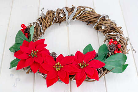 homemade christmas wreath with red flowers on wooden backgroundの写真素材
