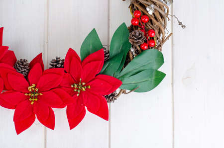 homemade christmas wreath with red flowers on wooden background, place for text.の写真素材