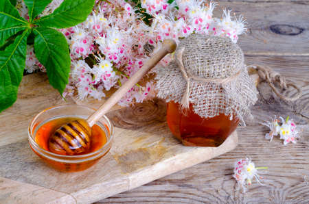 Fragrant chestnut honey in jar with blossom flowers.の写真素材