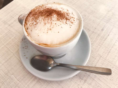 Cup of cappuccino with cinnamon on table