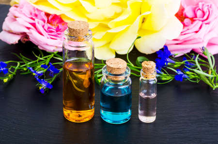 Three bottles of essential oil with fresh  flowers on black backgroundの写真素材