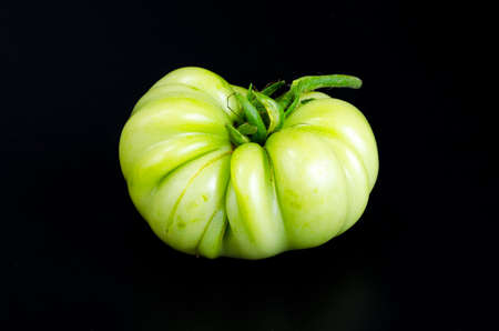 Green unripe tomato on black background. Studio Photoの写真素材