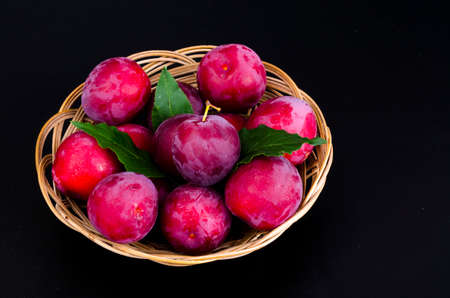 Ripe sweet plums in wicker bowl. Studio Photo