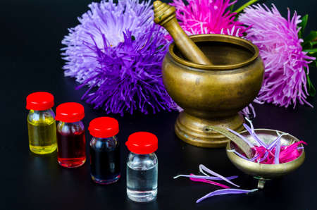 Glass bottles of essential oil with fresh flowers on black background. Studio Photoの写真素材