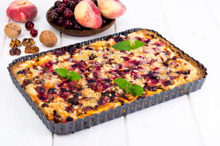 Homemade tart with berries, fruits and walnuts in shape on light background. Studio Photoの写真素材
