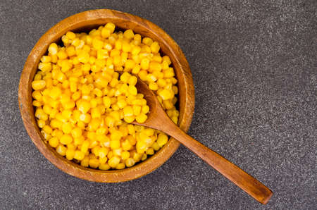 Sweet ripe canned corn in wooden bowl. Studio Photo