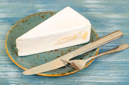 Piece of brie light cheese on blue wooden background. Studio Photoの写真素材