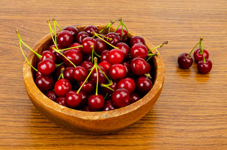 Wooden bowl with ripe sweet garden cherry. Studio Photo