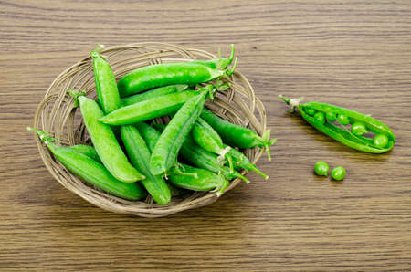 Ripe green peas pods on wooden background. Studio Photo