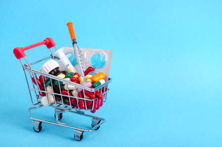 Buy medicine. Shopping basket with various medicinal, pills, tablets on blue background. Studio Photoの写真素材