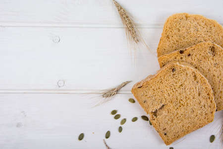 Wheat yeast rustic bread with pumpkin seeds on white wooden board background Studio Photo