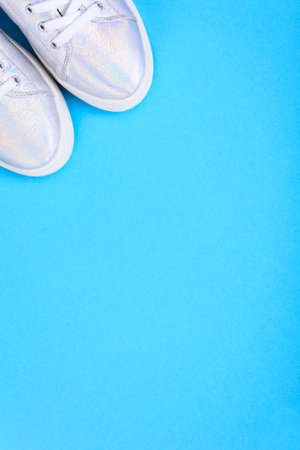 Silver sneakers on a blue background with place for text. Studio Photoの写真素材